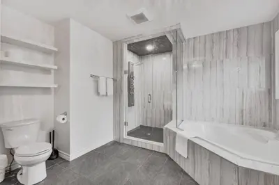 a white bathroom with a tub and a toilet at Luxe 4BR Retreat w Heated Pool Hot Tub and BBQ in Whitby