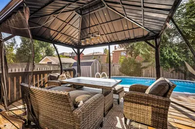 a patio with a table and chairs and a pool at Luxe 4BR Retreat w Heated Pool Hot Tub and BBQ in Whitby