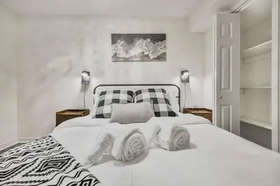 a bedroom with a white bed with a black and white blanket at Chic and Bright 1BR Apt with Free Wifi and Parking in Whitby