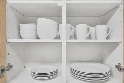 a cabinet filled with plates and cups and dishes at Chic and Bright 1BR Apt with Free Wifi and Parking in Whitby