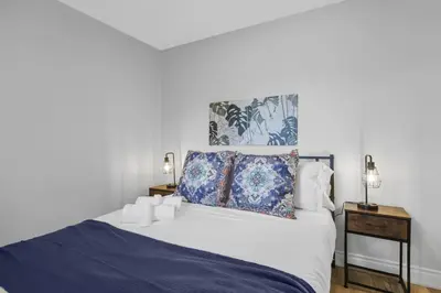 a bedroom with a white bed with a blue blanket at Stylish 3 BR Apt with Free Parking, Wifi and Patio in Whitby