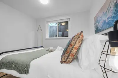 a bedroom with a white bed with a pillow on it at Stylish 3 BR Apt with Free Parking, Wifi and Patio in Whitby