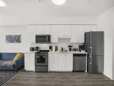 a kitchen with white cabinets and a stainless steel refrigerator at Stylish 1BR Condo in Prime Location with Parking and Wi Fi in Kitchener