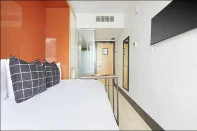 a bedroom with a white bed and an orange wall at The Beverley Hotel in Toronto