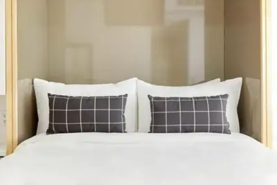 a white bed with four pillows on top of it at The Beverley Hotel in Toronto