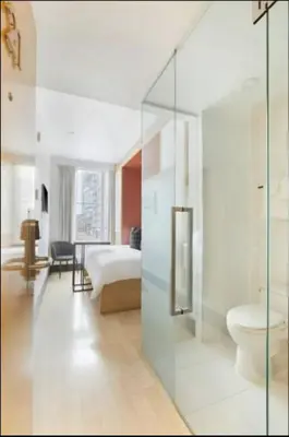 a bedroom with a bed and a bathroom with a glass wall at The Beverley Hotel in Toronto