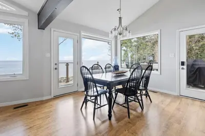 a dining room with a table and chairs and windows at Serene Waterfront Escape On Private Lane in Thornbury