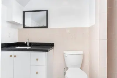 a white bathroom with a toilet and a sink at Cozy 3BR 2 Bath Lower Level Close to Shops in Richmond Hill