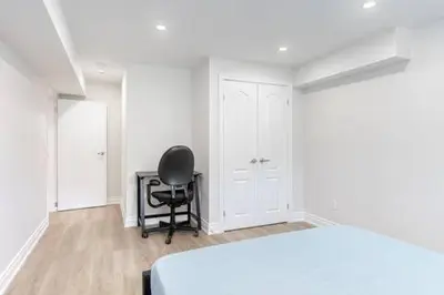 a bedroom with a black chair and a white bed at Cozy 1BR Lower Level Walking distance to shops in Richmond Hill