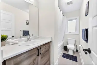 a white bathroom with a sink and a toilet at Joyful Haven|KingBed|Air Hockey| 10 mins to Falls in Thorold