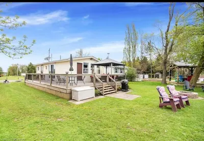 a house with a large yard with two chairs at Lakefront Lake Erie with Amazing Views 3BR Pet Friendly 1 HR from Hamilton and Niagara