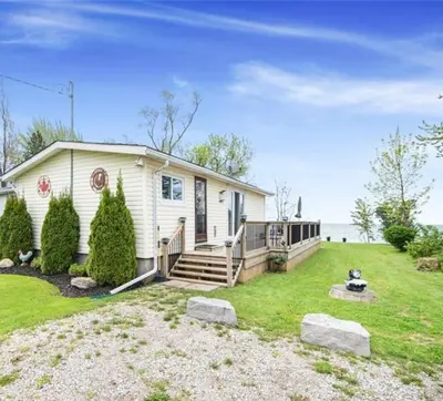 a white house with a porch and a yard at Lakefront Lake Erie with Amazing Views 3BR Pet Friendly 1 HR from Hamilton and Niagara