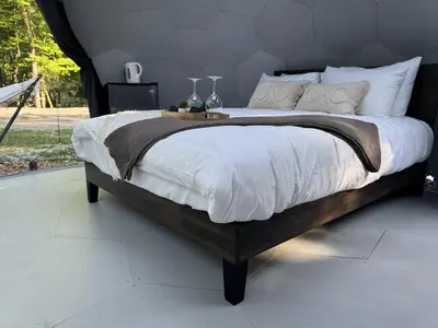 a bedroom with a large bed with white sheets at Rare Mirrored Glamping Dome in Severn
