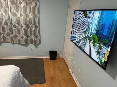 a bedroom with a large flat screen tv on a wall at Renaissance Guest House in Oshawa