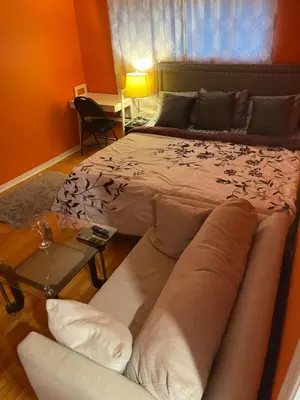a bedroom with a bed with a couch and a table at Renaissance Guest House in Oshawa