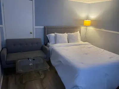 a small bedroom with a bed and a chair at Renaissance Guest House in Oshawa