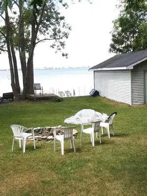 a table and chairs sitting in the grass near the water at Waterfront Comfy Guesthouse, PEC in Carrying Place