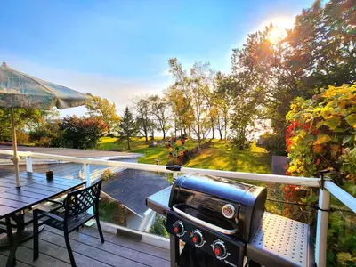 a balcony with a grill and a table on a deck at Waterfront Comfy Guesthouse, PEC in Carrying Place
