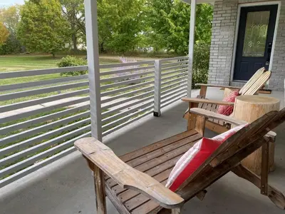 a porch with two wooden chairs and a table at Private Beach Hot Tub A Vacay to Remember in Hillier