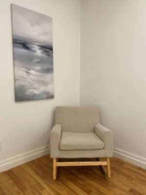 a chair in a room with a painting on the wall at Private Beach Hot Tub A Vacay to Remember in Hillier