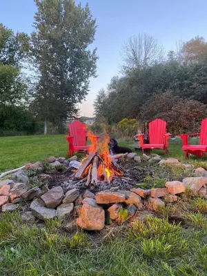 a fire pit with red chairs and a fire burns at Private Beach Hot Tub A Vacay to Remember in Hillier