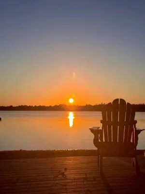 a chair sitting on a dock watching the sunset at Private Beach Hot Tub A Vacay to Remember in Hillier