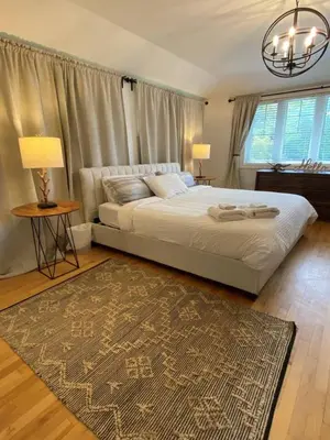 a bedroom with a large bed with two lamps and a rug at Private Beach Hot Tub A Vacay to Remember in Hillier