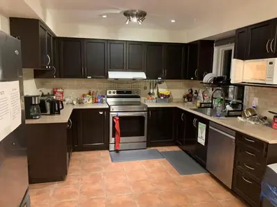 a kitchen with black cabinets and a stove top oven at Private comfortable M1 bedroom in Mississauga