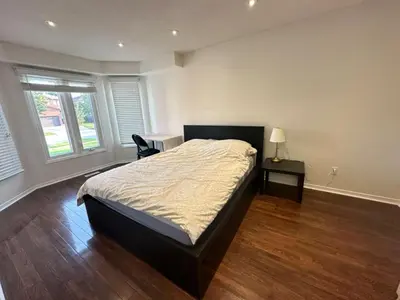 a bedroom with a bed and a desk and two windows at Private comfortable M1 bedroom in Mississauga