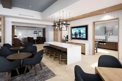 a living room with tables and chairs and a kitchen at Staybridge Suites Aurora East by IHG in Aurora