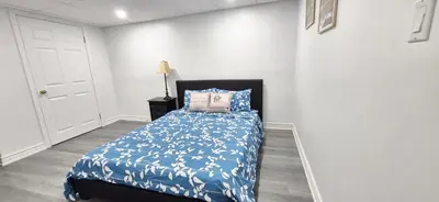 a bedroom with a bed with a blue comforter at Pacific Mall Bright & Cozy Rooms with Privated Bathrooms in Toronto
