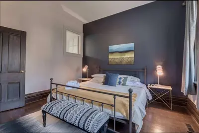 a bedroom with a bed with a blue wall at Modern Industrial Suite w Private Patio - The Roland in Toronto