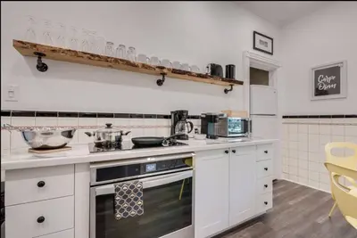 a kitchen with white cabinets and a stove top oven at Modern Industrial Suite w Private Patio - The Roland in Toronto