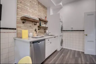 a kitchen with white cabinets and a brick wall at Modern Industrial Suite w Private Patio - The Roland in Toronto