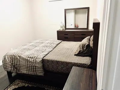 a bedroom with a bed with a dresser and a mirror at Heaven on Earth in Ajax