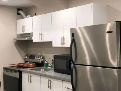 a kitchen with a stainless steel refrigerator and white cabinets at Heaven on Earth in Ajax