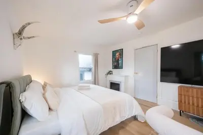a white bedroom with a bed and a tv at County Cove - Newly Renovated Century Home in Carrying Place
