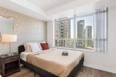 a bedroom with a bed and a large window at Luxe 3BR 2 Bath Condo Steps from Square one Mall in Mississauga
