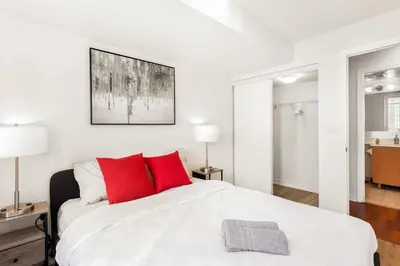 a white bedroom with red pillows on a bed at Luxe 3BR 2 Bath Condo Steps from Square one Mall in Mississauga
