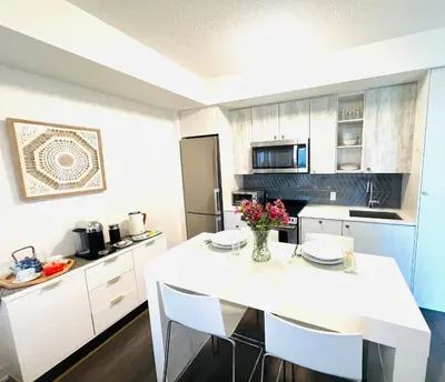 a kitchen with a white table and white cabinets at Lakeview in Toronto