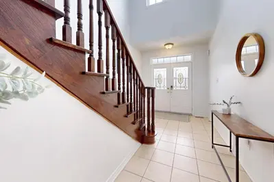 a hallway with a wooden staircase and a mirror at Charming 4-bed Home Away From Home in Brampton, ON in Brampton