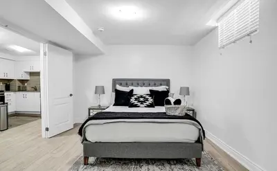 a bedroom with a large bed in a white room at Stylish Modern 2-bedroom Basement Suite in Brampton