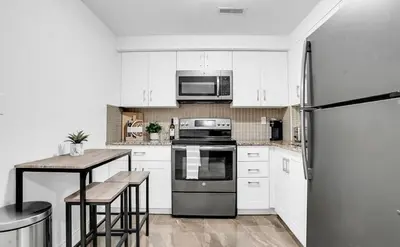a kitchen with white cabinets and a stainless steel refrigerator at Stylish Modern 2-bedroom Basement Suite in Brampton