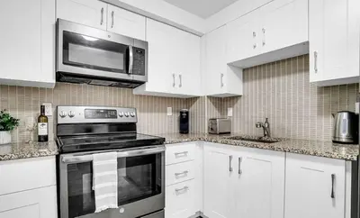 a kitchen with white cabinets and a stove and a microwave at Stylish Modern 2-bedroom Basement Suite in Brampton
