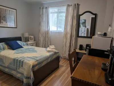 a bedroom with a bed and a table and a mirror at Cozy home away from home, close to hospital, college, and university with free parking in Peterborough