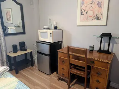 a room with a desk and a microwave on top of a refrigerator at Cozy home away from home, close to hospital, college, and university with free parking in Peterborough