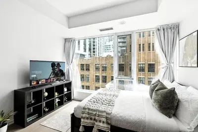 a bedroom with a bed and a large window at Modern Studio Retreat in Downtown Toronto in Toronto