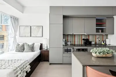 a white bedroom with a bed and a kitchen at Modern Studio Retreat in Downtown Toronto in Toronto