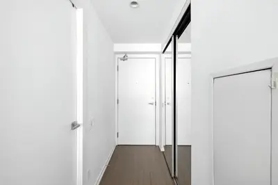 a hallway with white walls and a glass door at Modern Studio Retreat in Downtown Toronto in Toronto