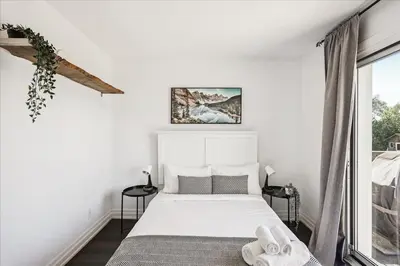 a white bedroom with a bed and a window at Bright 3-BDRM House, Family Home & Parking, YYZ Airport in Mississauga